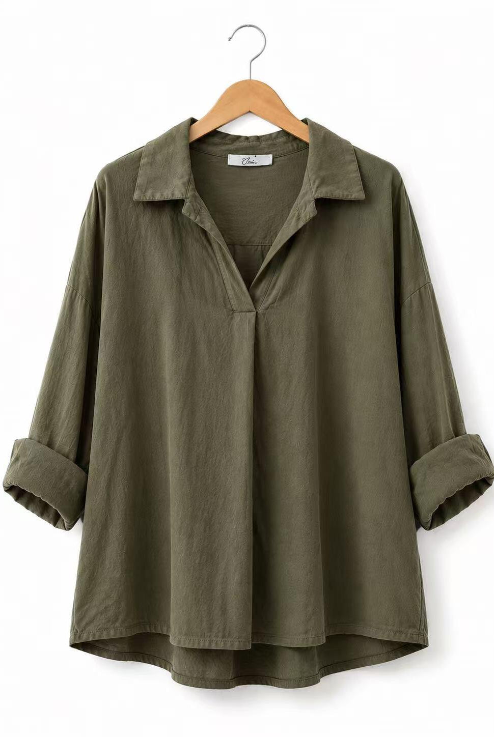 An olive green long-sleeve collared shirt with rolled cuffs, hanging on a wooden hanger against a plain white background.