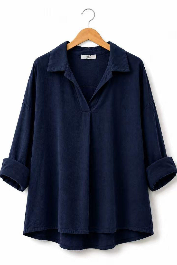 A dark navy blue long-sleeve collared shirt with rolled cuffs, hanging on a wooden hanger against a plain white background.