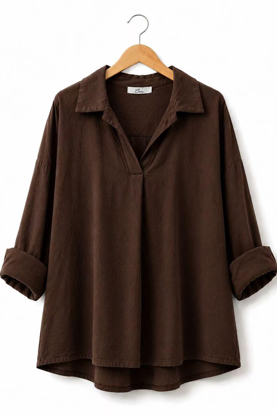 A dark brown long-sleeve collared shirt with rolled cuffs and a split V-neckline, hanging on a wooden hanger against a plain white background.
