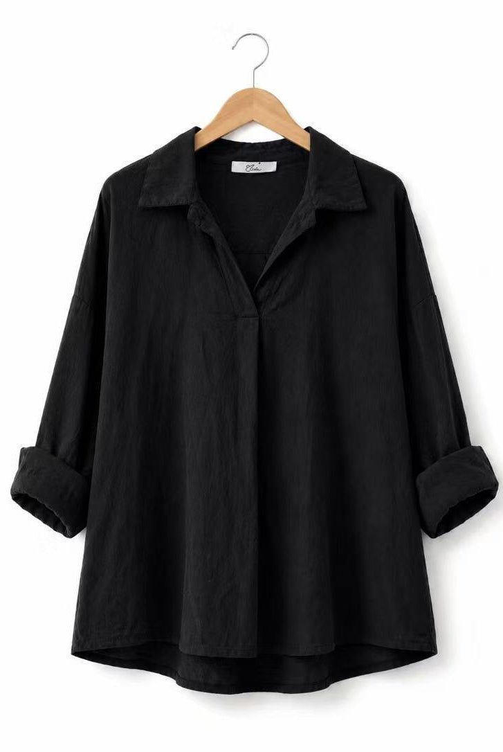 A black long-sleeve shirt with a relaxed, oversized fit, displayed on a wooden hanger against a plain white background.