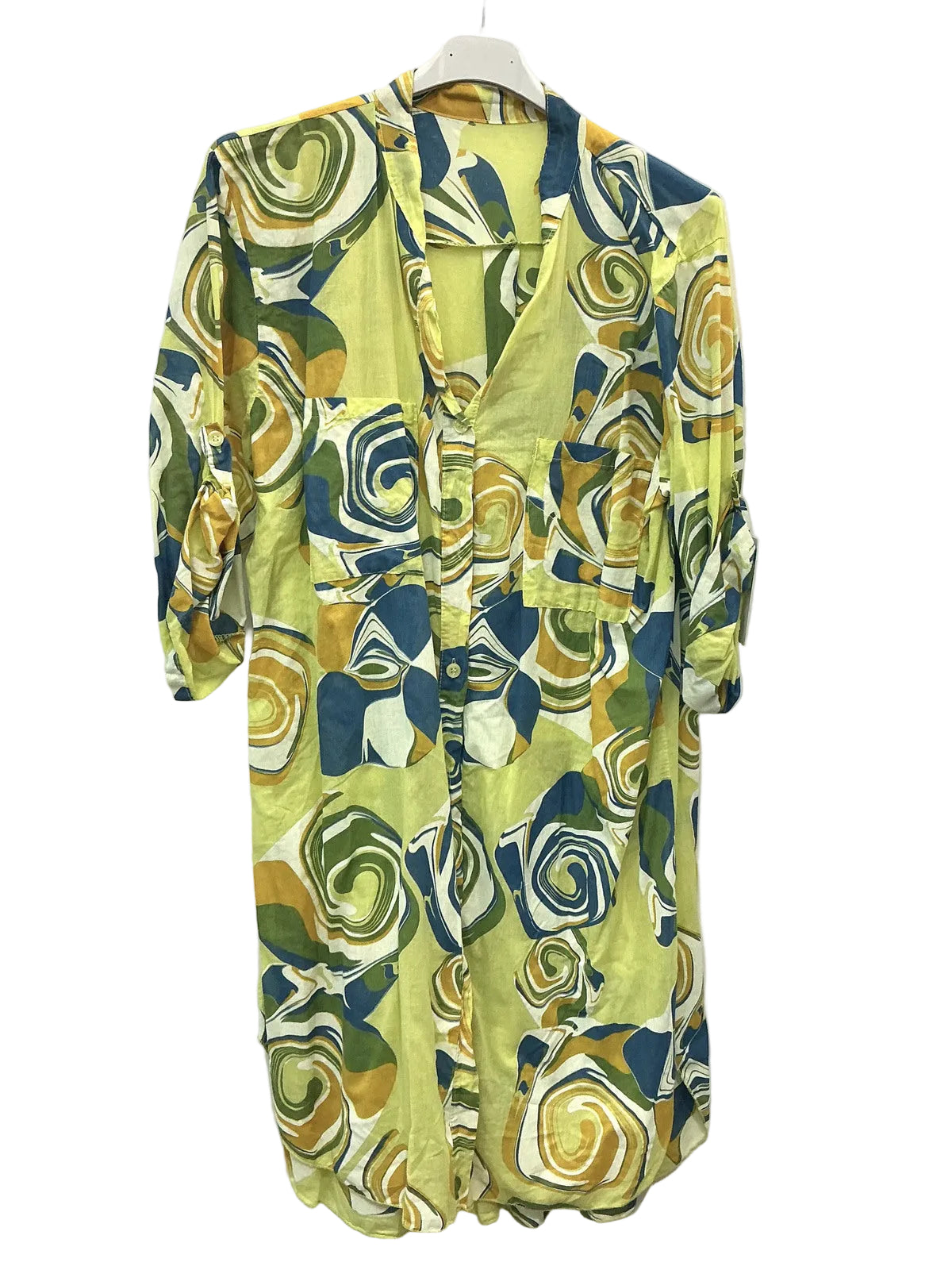 A long-sleeve button-front shirt dress with a vibrant abstract floral pattern in yellow, green, blue, and white, hanging on a white hanger against a plain white wall.