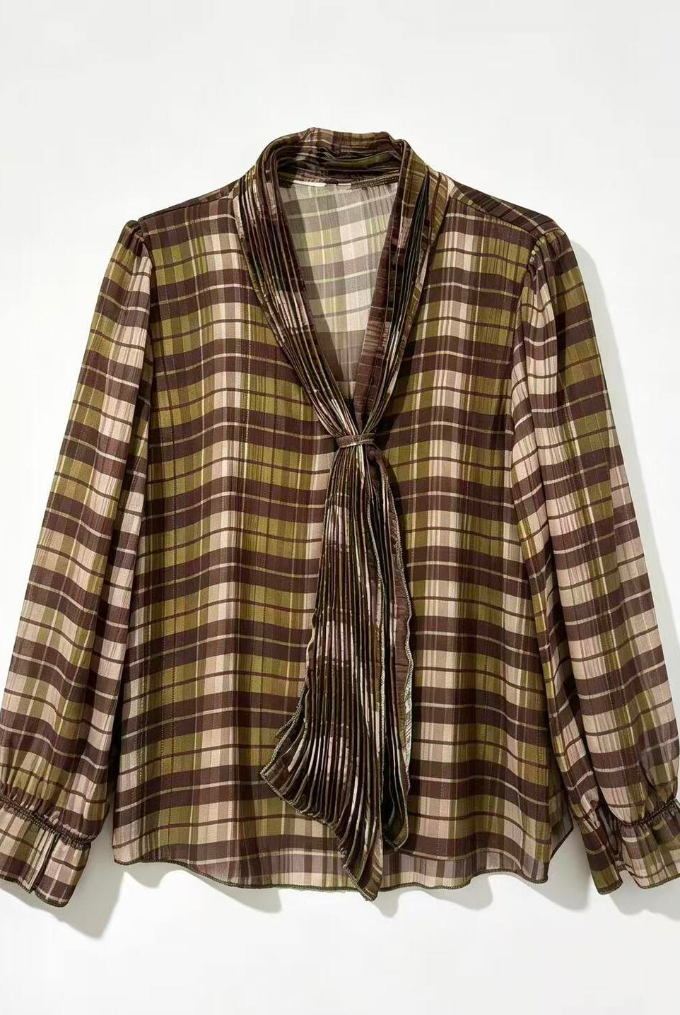 A long-sleeve plaid blouse with a shawl collar and front tie, shown hanging against a plain white background.
