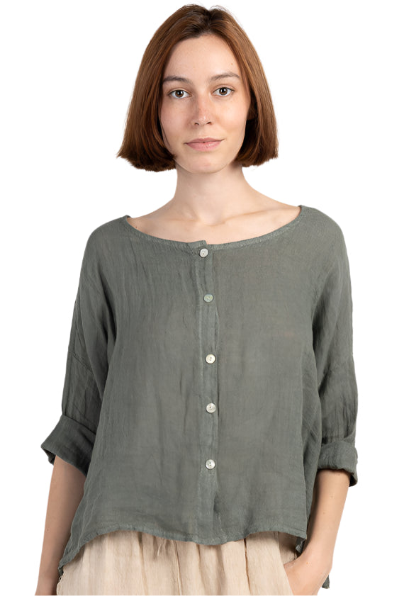 Woman wearing a green button-up shirt and beige pants on a white background