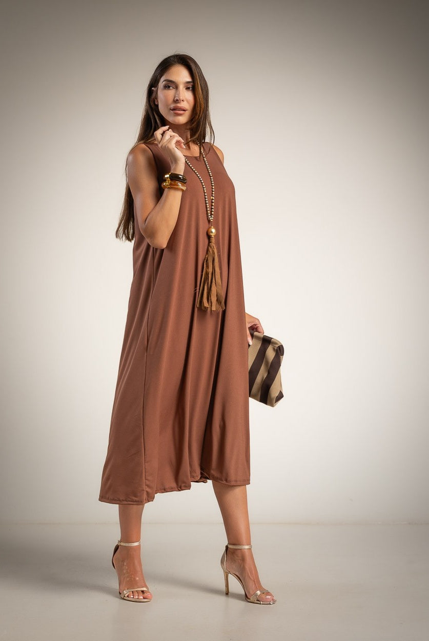 A woman models a sleeveless, flowy midi dress in a warm brown shade.