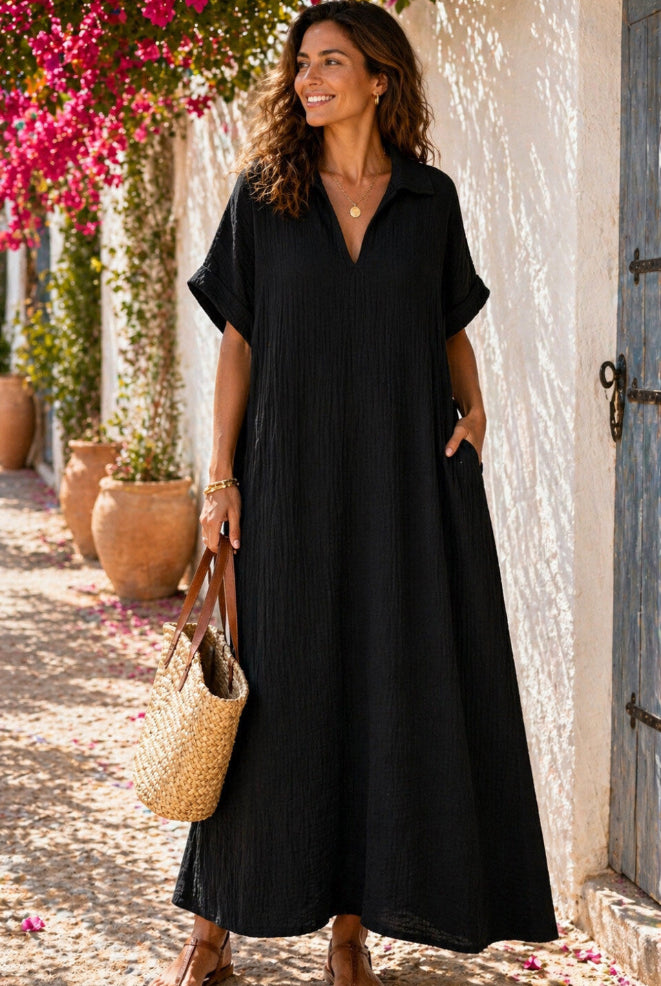 Woman in a black dress standing outdoors with flowers and a building in the background