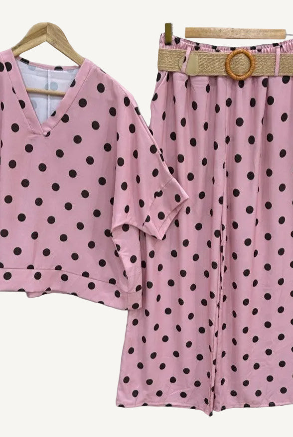 Pink polka dot outfit with top and pants on hangers against a white background