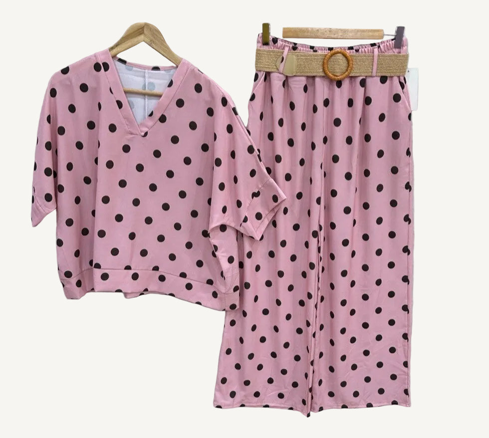 Pink polka dot outfit with top and pants on hangers against a white background
