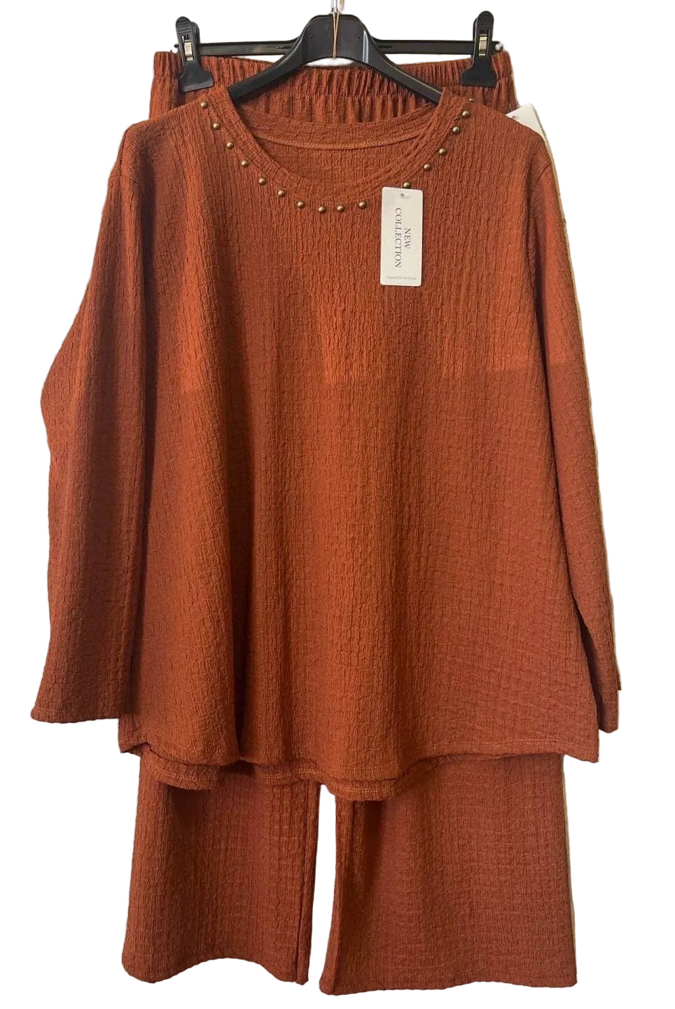A rust-orange two-piece matching set consisting of a textured long-sleeve tunic top with a studded neckline and matching wide-leg pants