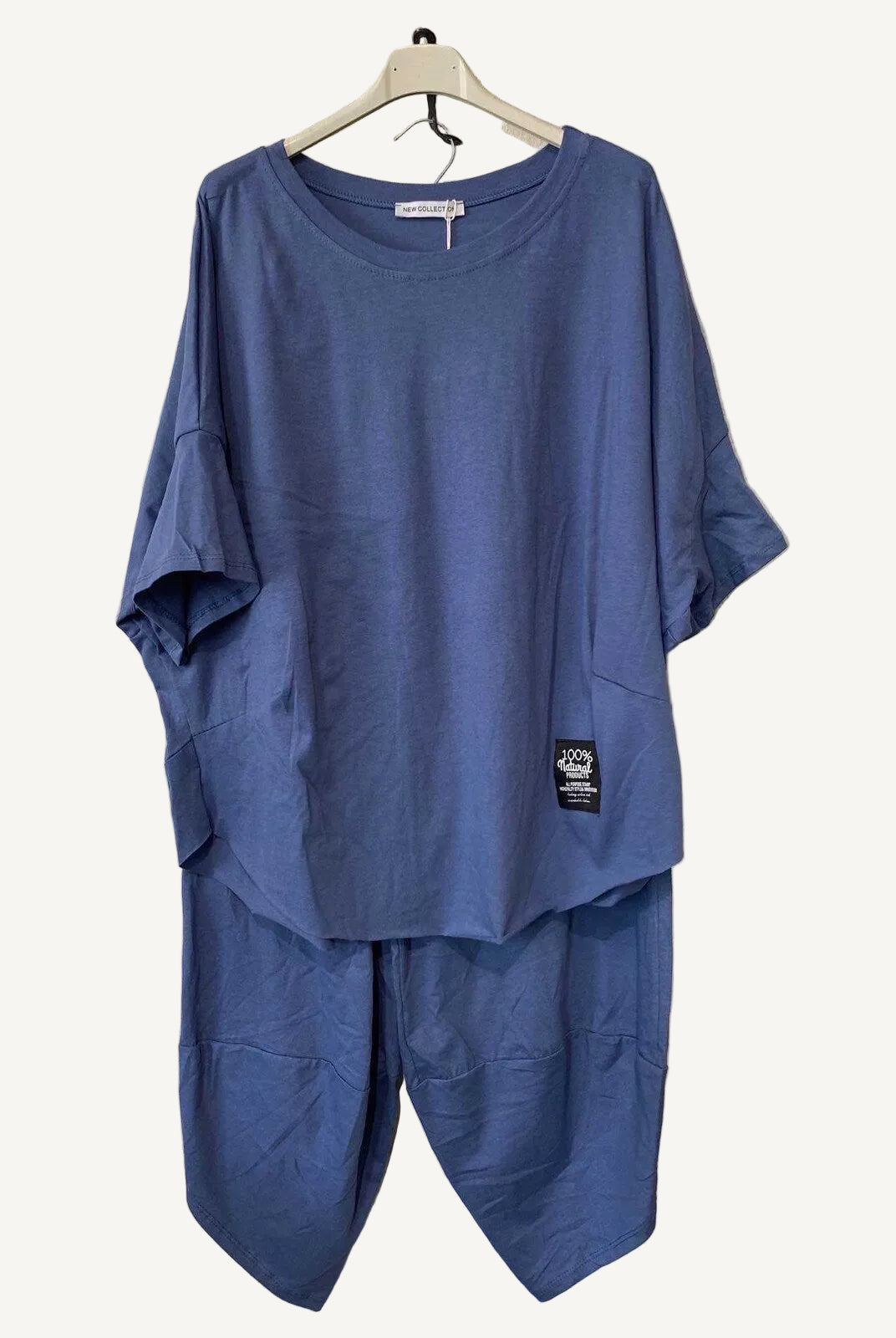 Blue outfit with a t-shirt and pants hanger against a textured wall.