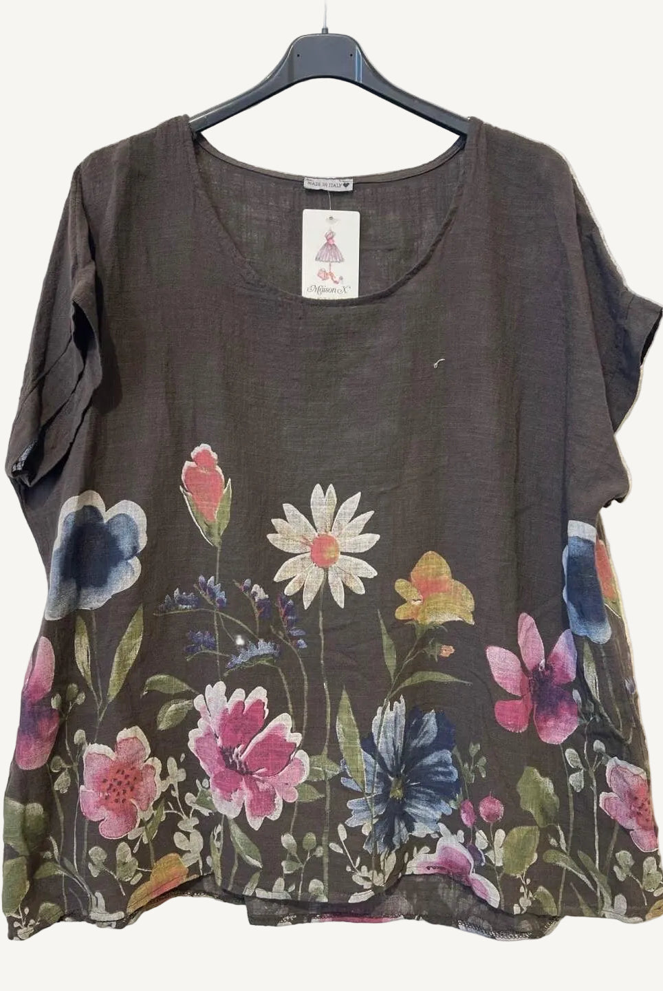 Floral-patterned brown top on a hanger against a textured white background