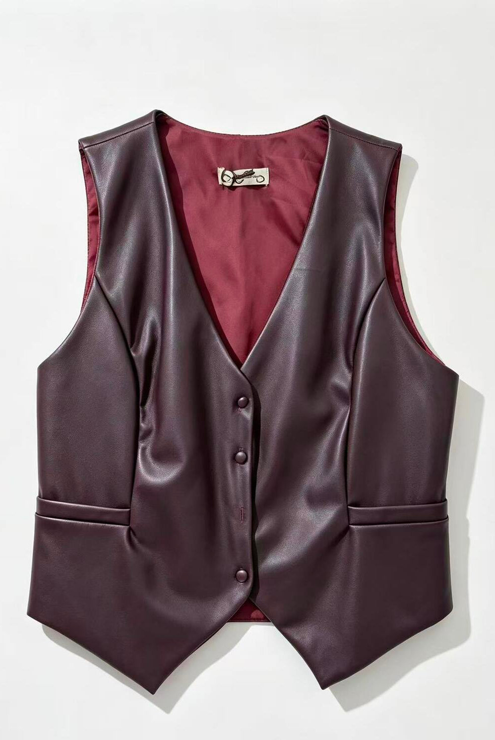 A dark plum faux-leather vest with a V-neck, three-button front, and side pockets, displayed flat against a light off-white background.