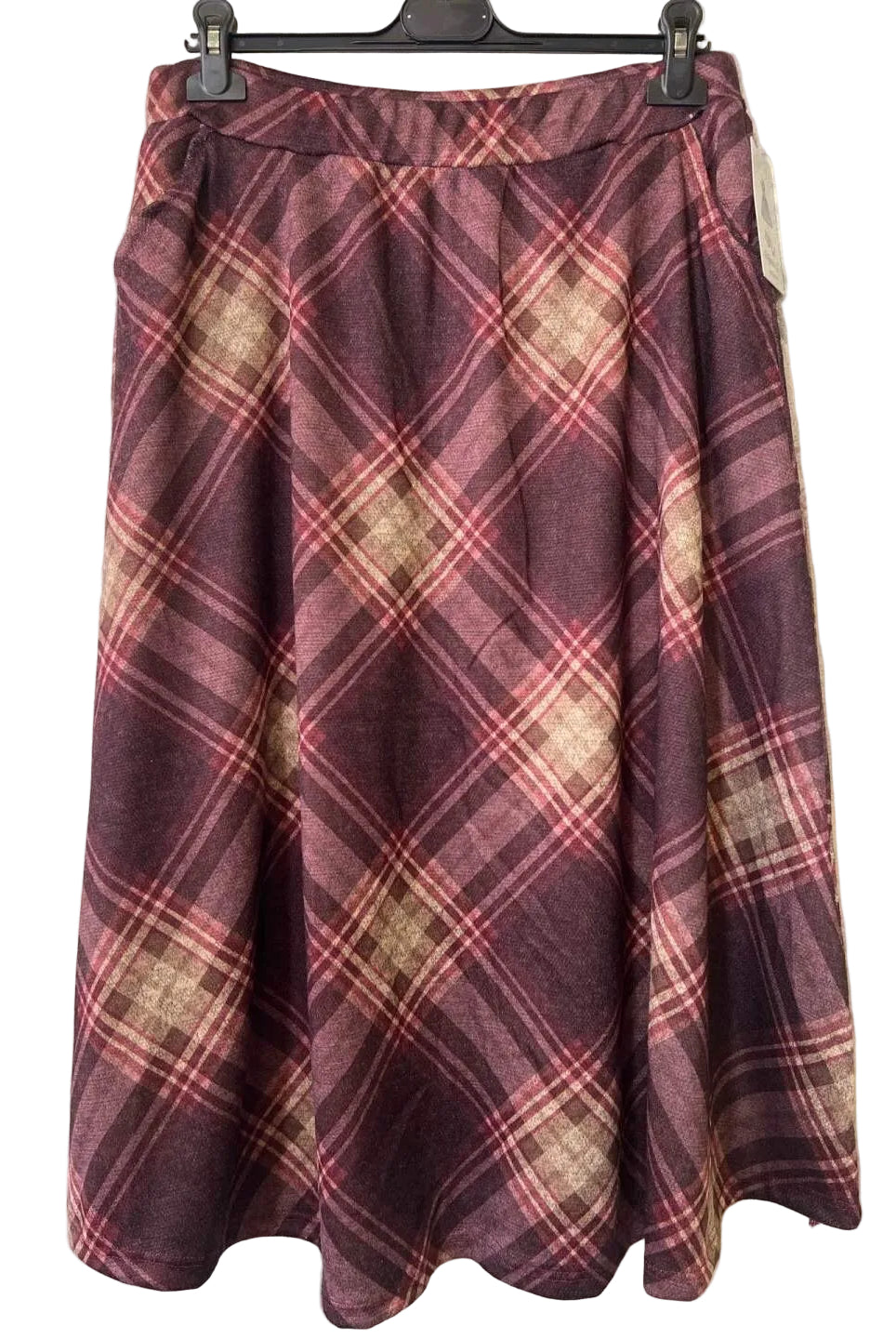 A pleated A-line skirt in a burgundy and beige plaid pattern, hanging on a black hanger against a textured gray wall.