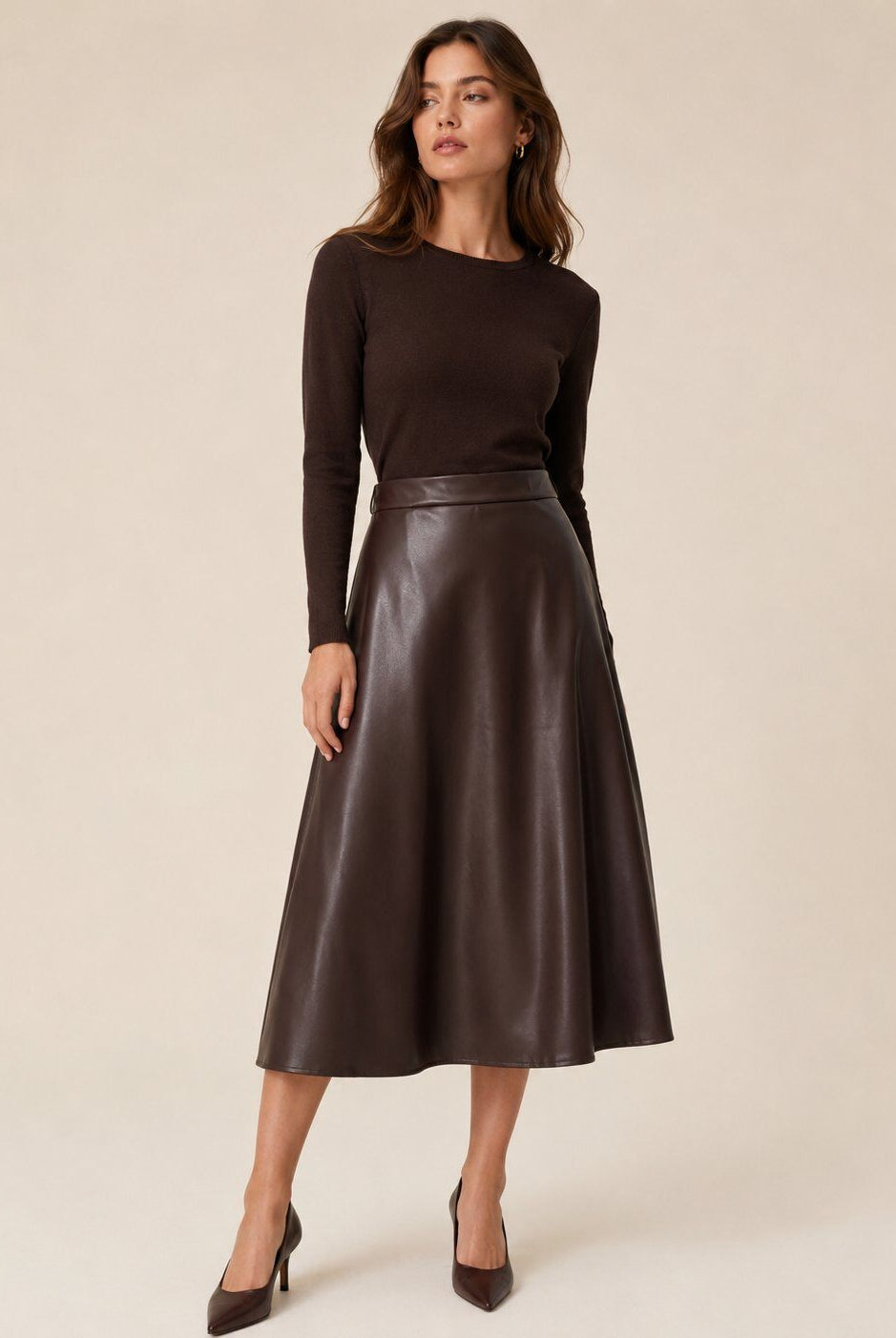 A woman modeling a dark brown long-sleeve knit top and a matching dark brown leather midi skirt