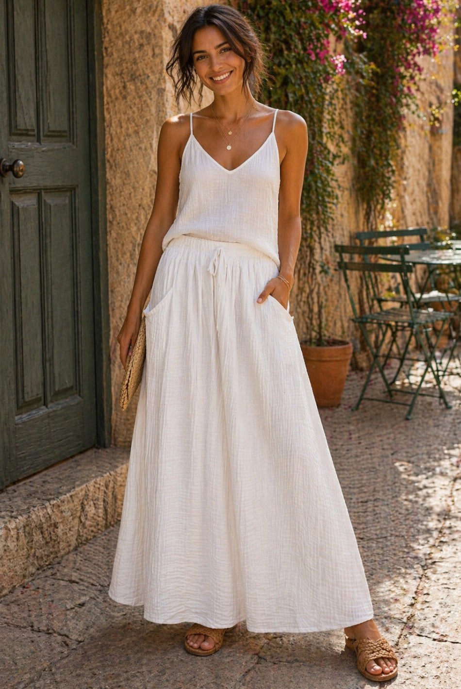 Woman in a white skirt standing outdoors near a building with plants.