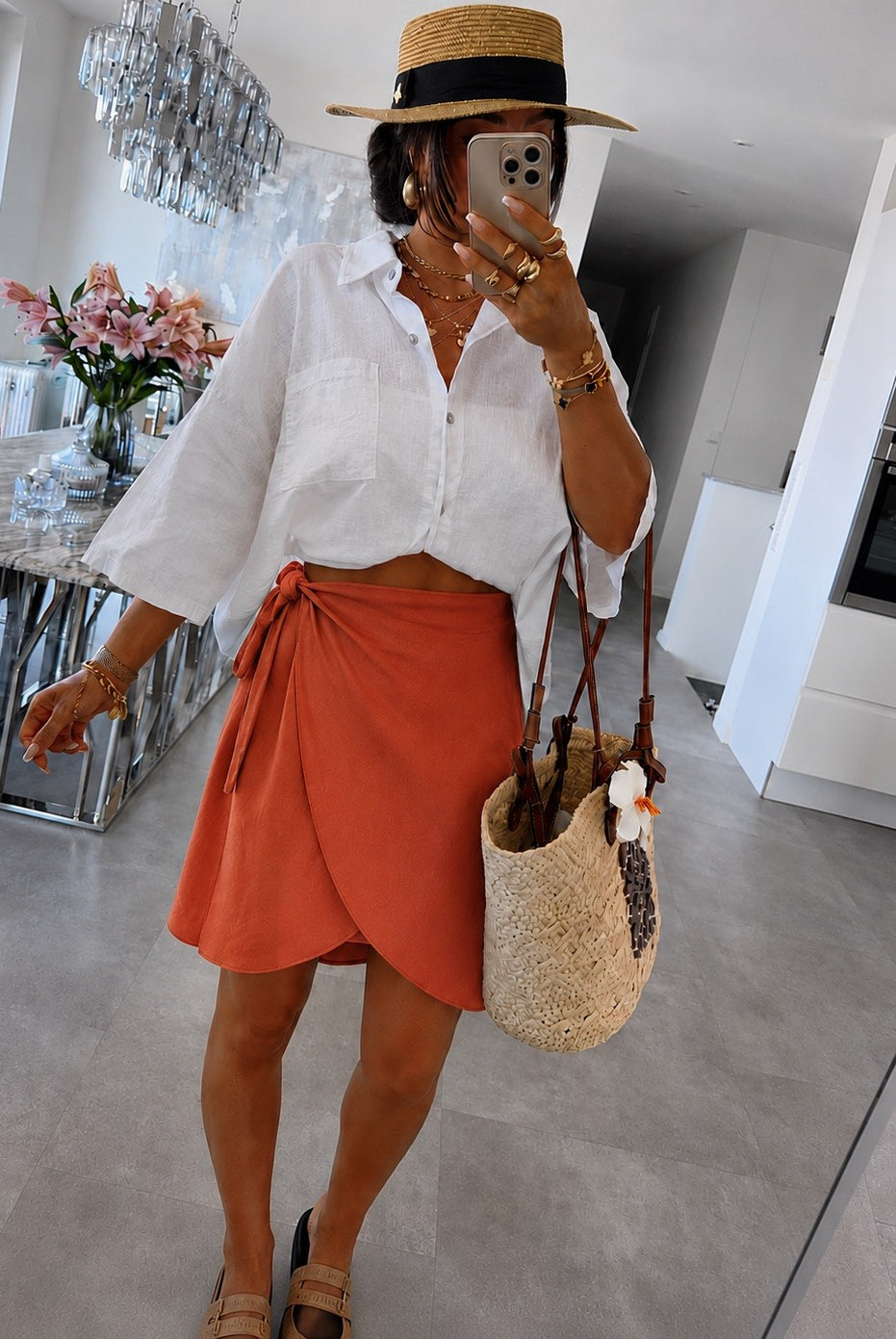 A woman wearing a white button-down shirt, a rust-orange wrap skirt
