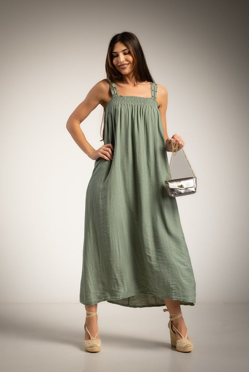 A woman modeling a green maxi dress with a smocked bodice and studded straps