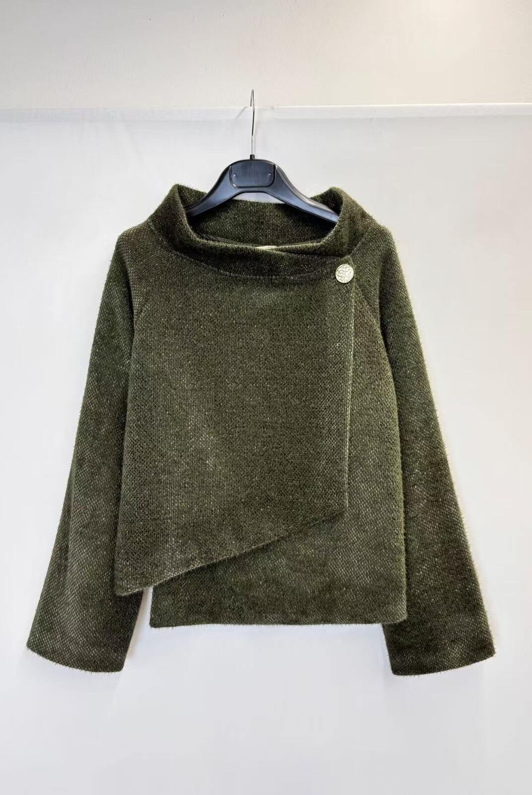 An olive green textured knit wrap jacket with a high mock neck and asymmetrical draped front, hanging on a black hanger against a plain white wall.