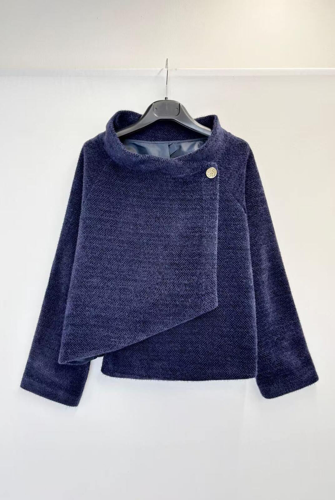 A navy blue textured knit wrap jacket with a single button closure, hanging on a black hanger against a plain white wall.