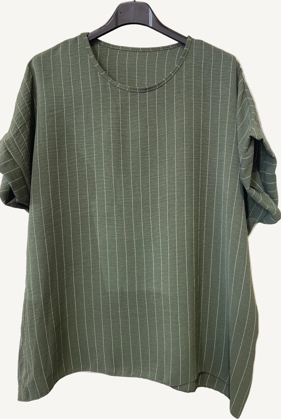 Green striped shirt on a hanger against a textured white background