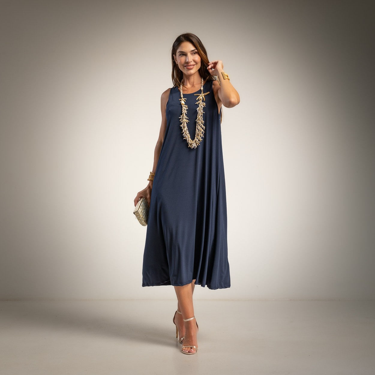 A woman modeling a sleeveless navy blue midi dress with a flowing silhouette.