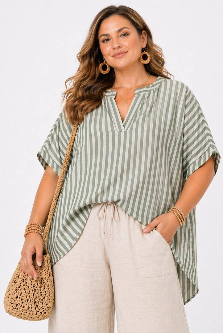 Woman wearing a green and white striped shirt with beige pants, holding a woven bag on a white background
