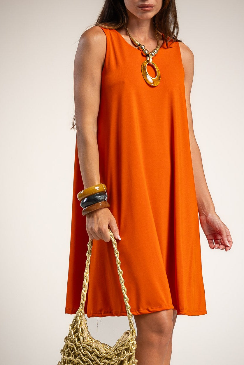 A woman wearing a sleeveless bright orange A-line dress, holding a woven straw bag