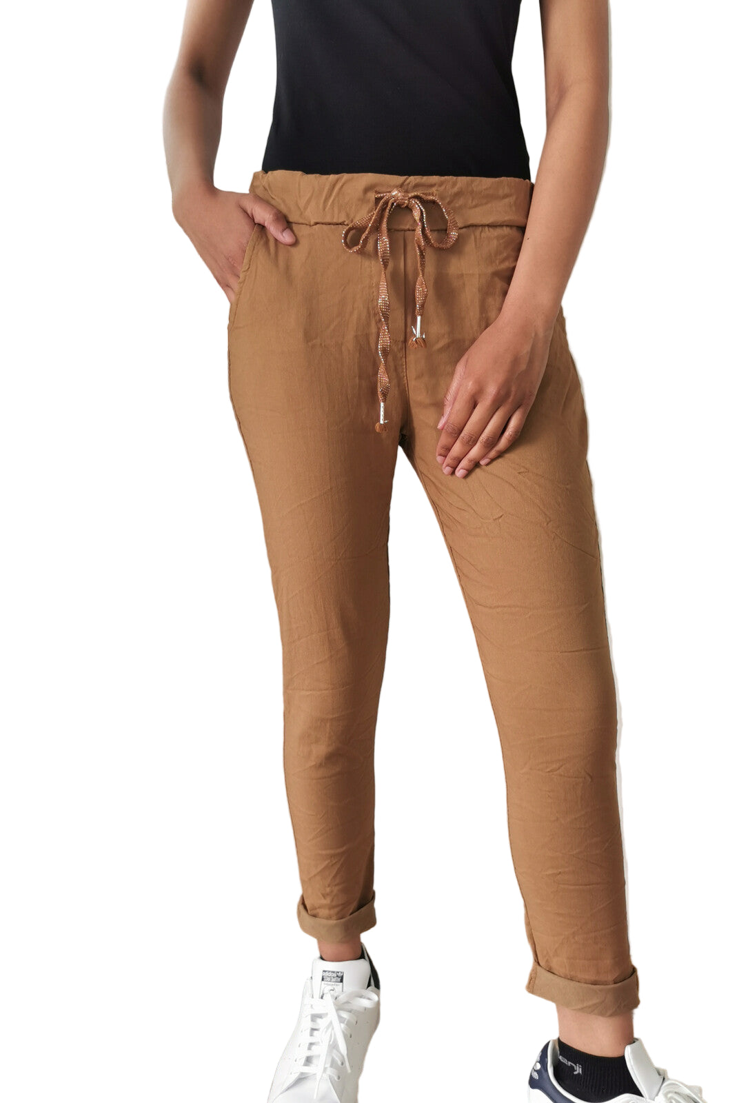 Person wearing brown jogger pants with a white wall and radiator in the background