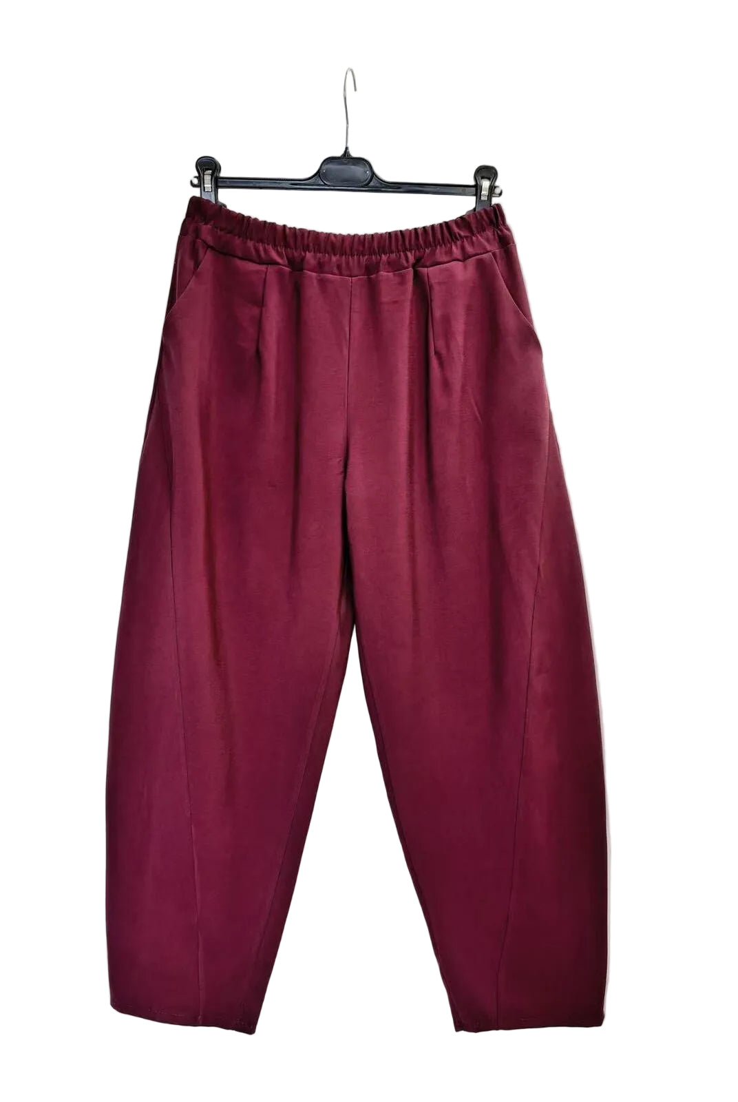 A pair of loose-fitting, pleated trousers in a deep burgundy or maroon color, hanging from a black hanger against a plain white backdrop.