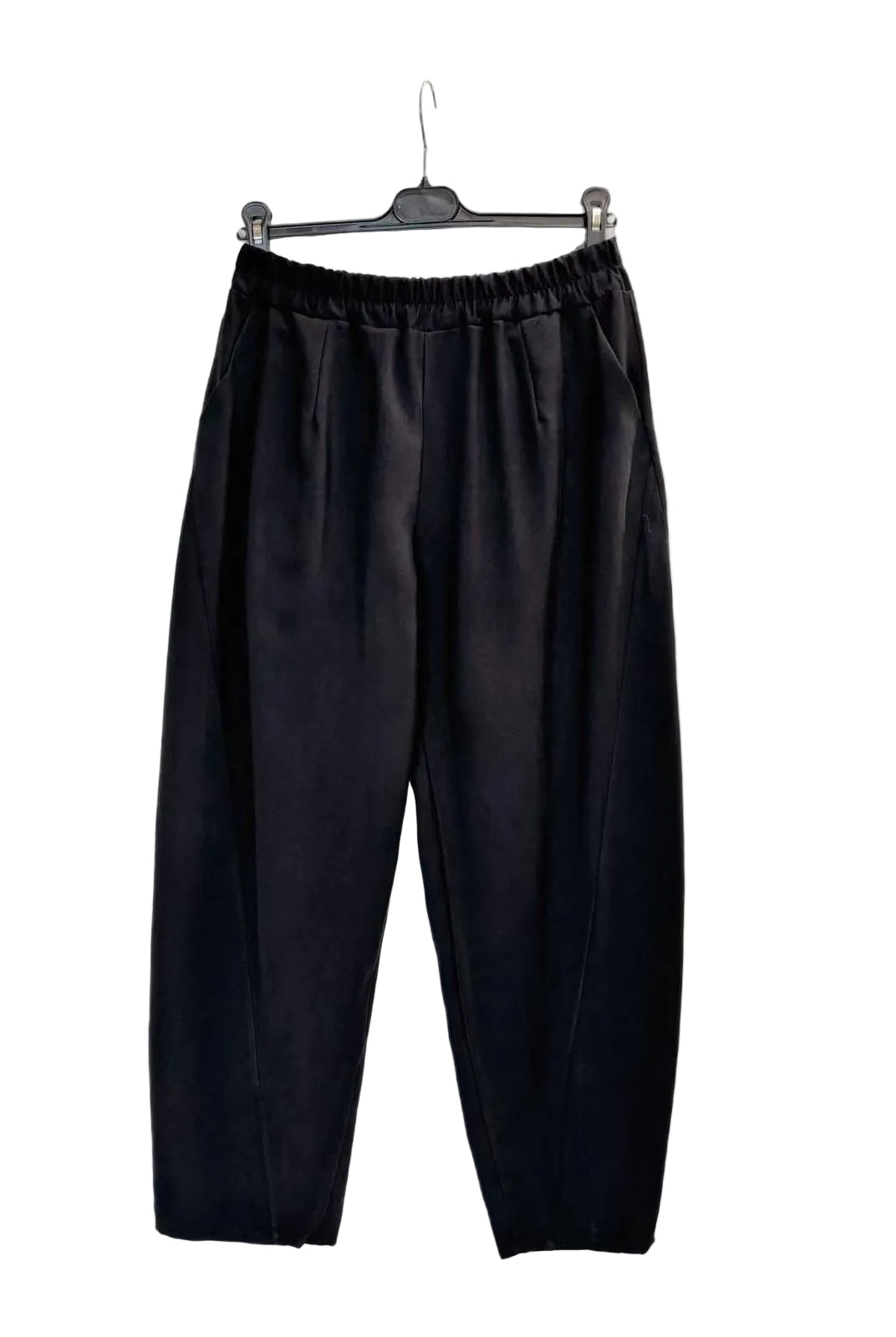 Black wide-leg cropped pants with an elastic waistband, hanging on a black hanger against a plain white wall.