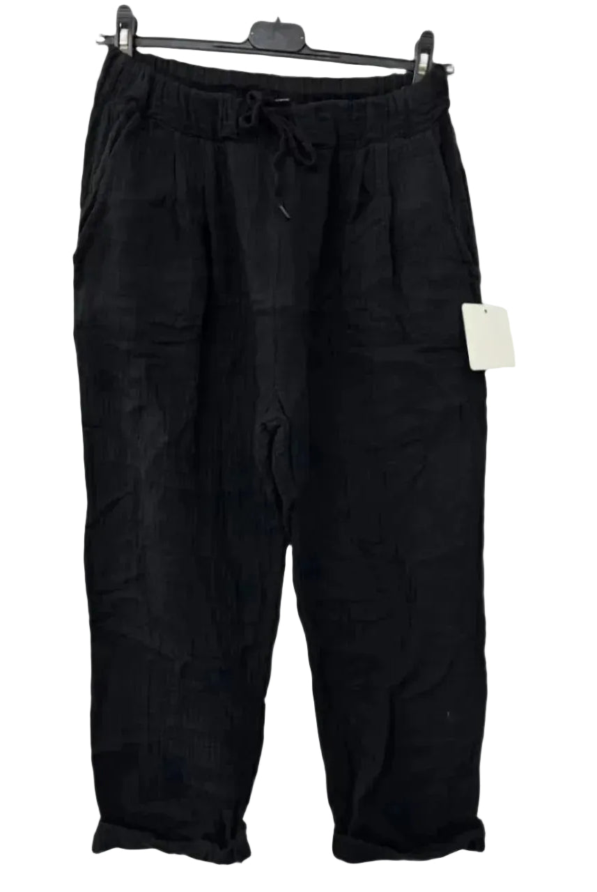 Black cotton gauze trousers with elasticated drawstring waist, displayed on a hanger.