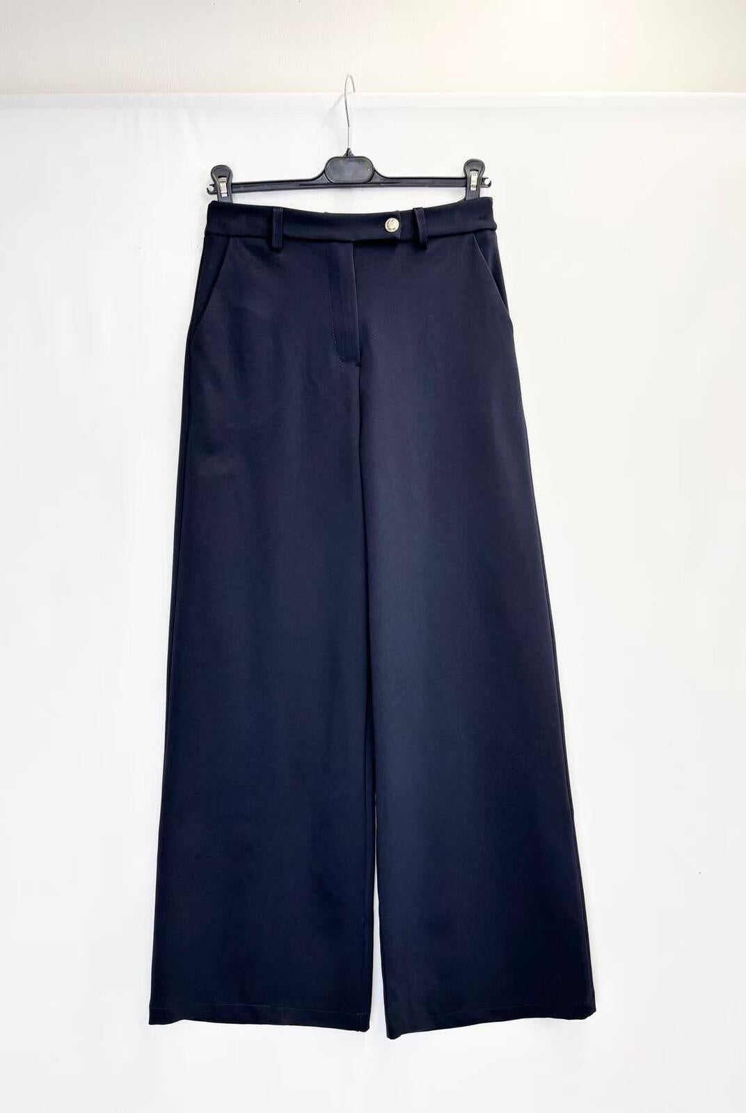 A pair of dark navy blue trousers hanging on a black hanger against a plain white background.