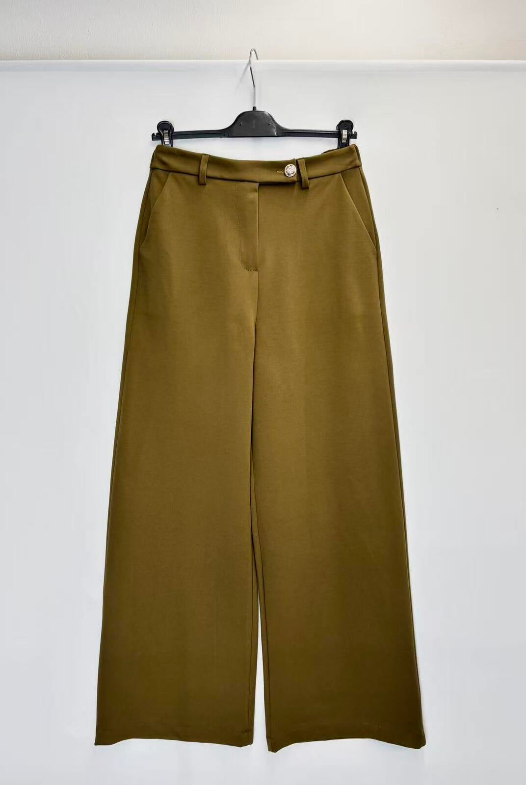 A pair of olive green wide-leg cropped pants hanging on a black hanger against a plain white wall.