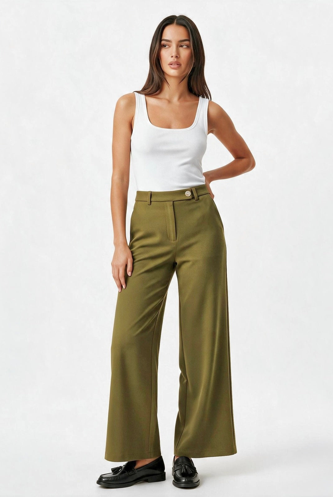 A model wearing olive green wide-leg trousers with a button waistband, styled with a white tank top and black loafers, against a plain white studio background.