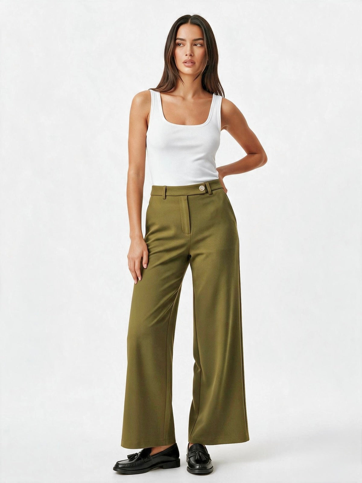 A model wearing olive green wide-leg trousers with a button waistband, styled with a white tank top and black loafers, against a plain white studio background.