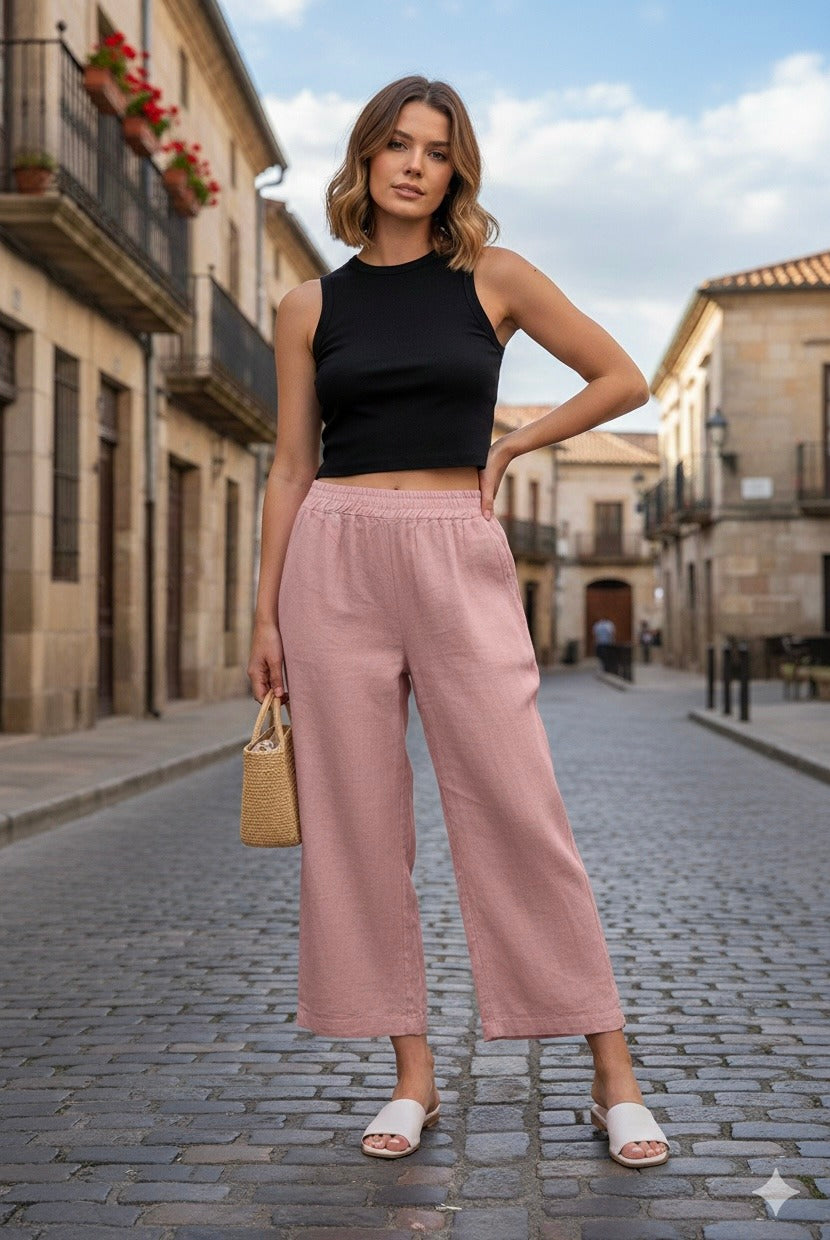 Woman in black top and pink pants standing on a street with buildings in the background