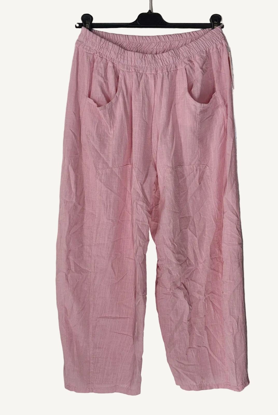 Pink pants on a hanger against a textured white wall