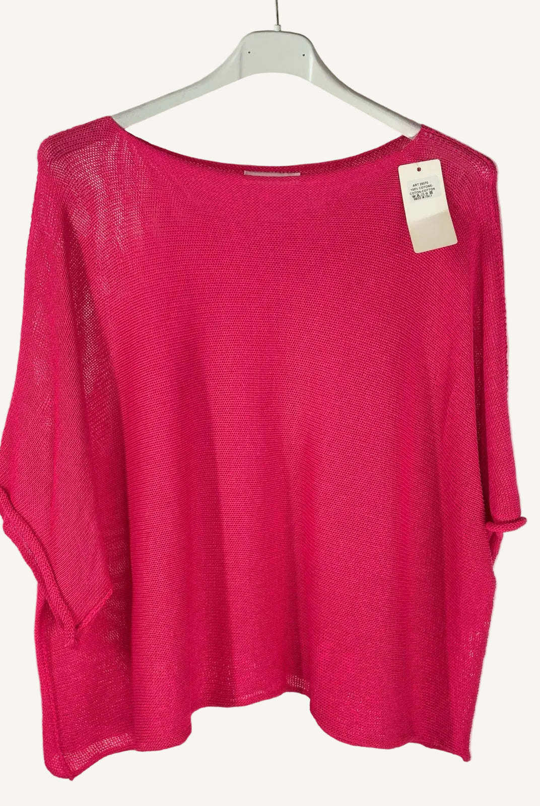 Pink sweater on a hanger with a visible tag against a neutral background