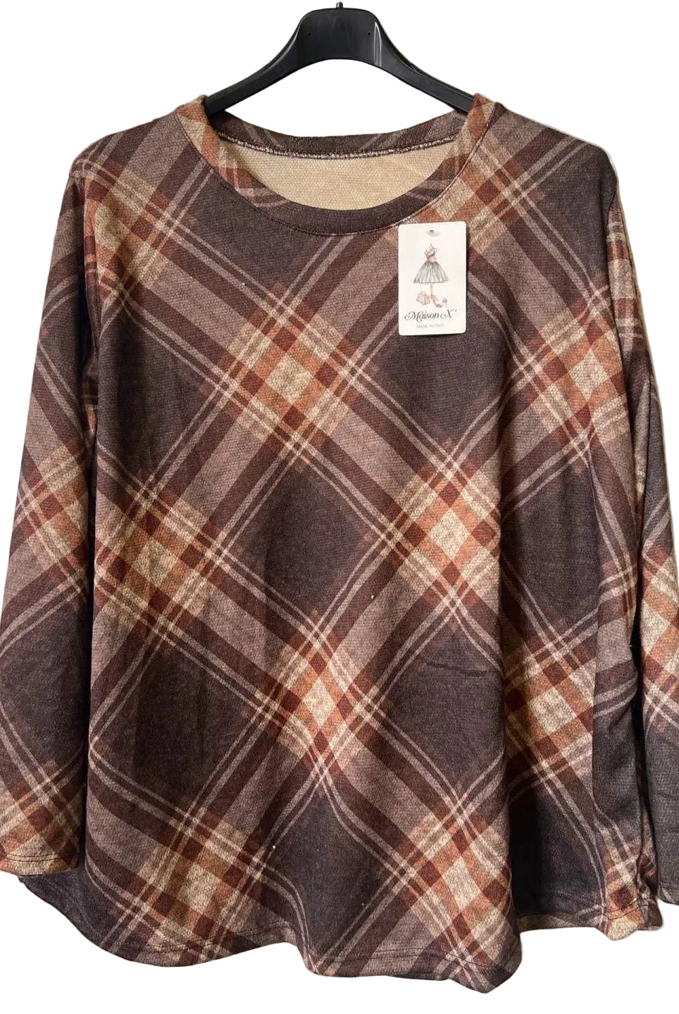 A long-sleeve plaid top hanging on a black hanger against a textured gray wall. The top features a brown, rust-orange, and beige plaid pattern