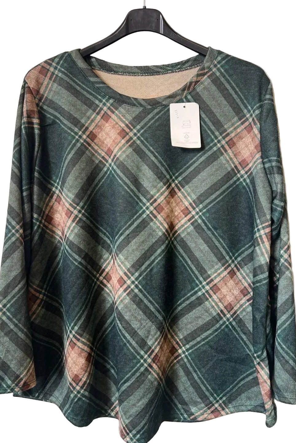 A women's long-sleeve plaid top hanging on a black hanger against a textured gray wall. The top features a muted green, brown, and beige tartan pattern