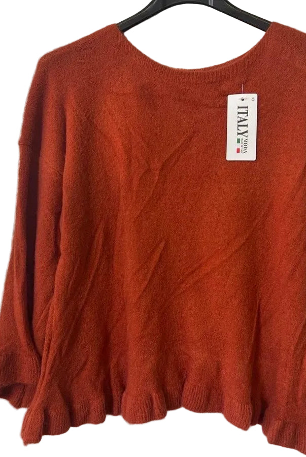 A rust-orange knit sweater with long sleeves and a ruffled hem,