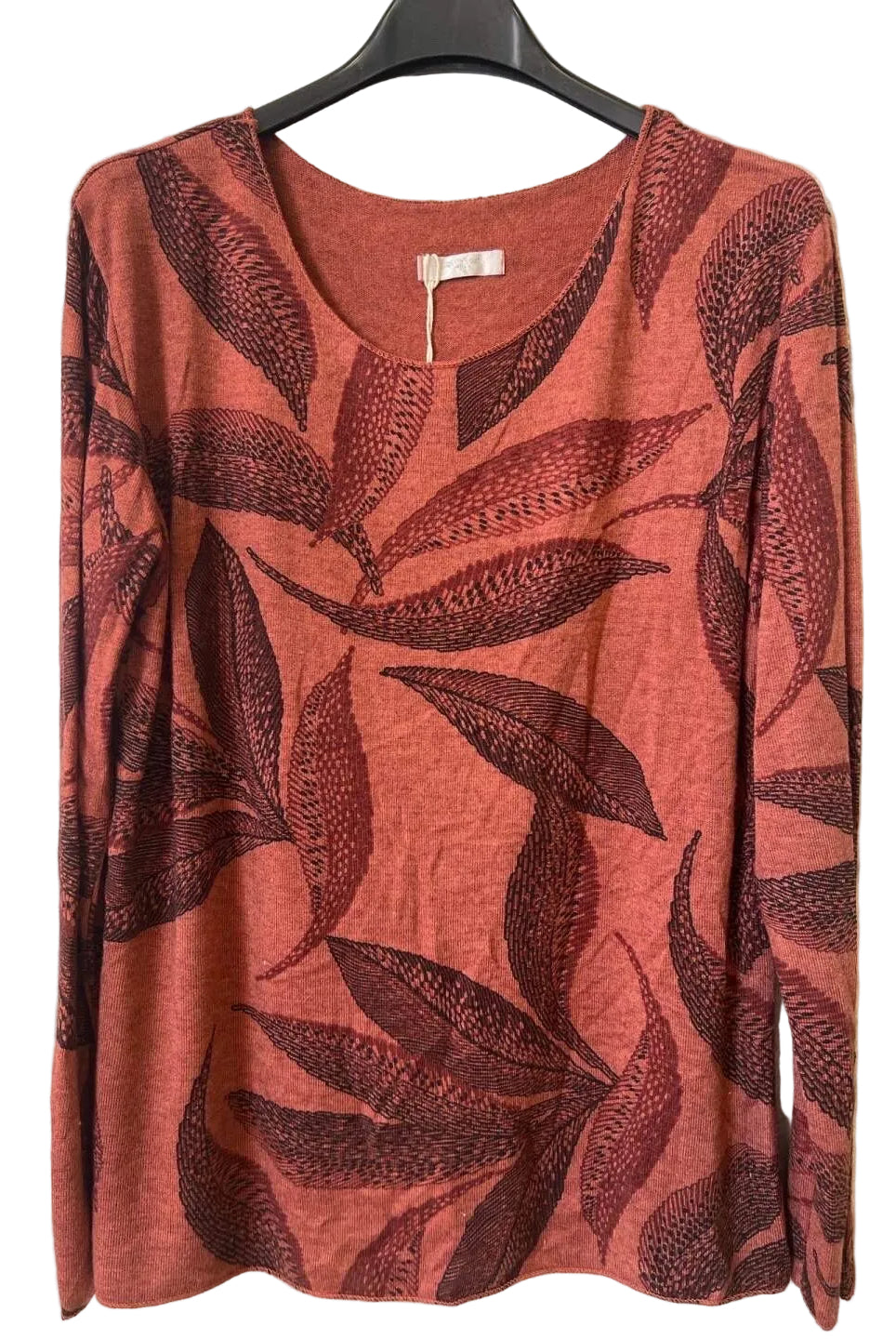 A rust-orange long-sleeve top with a dark reddish-brown leaf pattern,