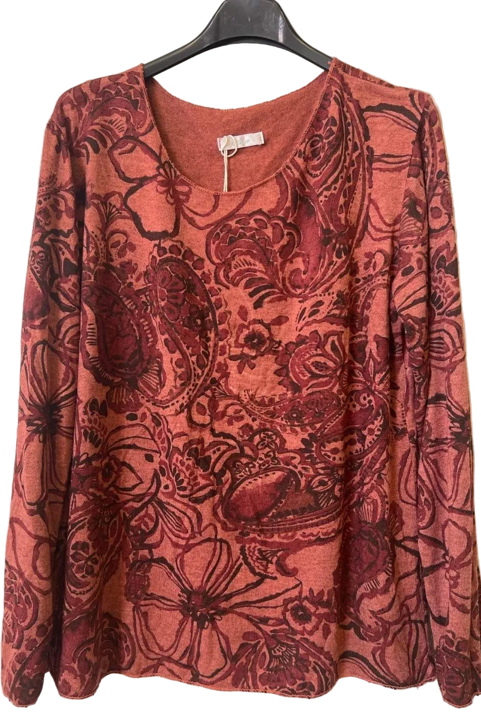 A long-sleeve V-neck top with an all-over floral and paisley print in rust red and dark burgundy,