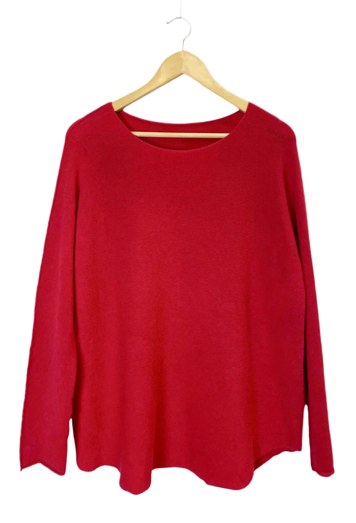 A bright red long-sleeve knit top hanging on a light wood hanger against a plain off-white background.