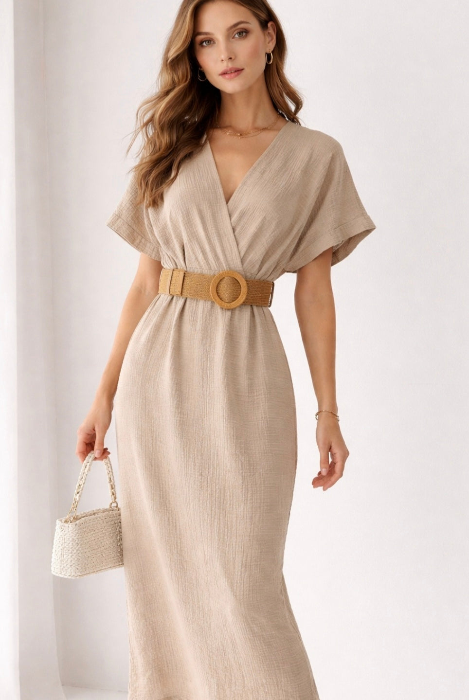 Woman wearing a beige dress with a belt on a white background