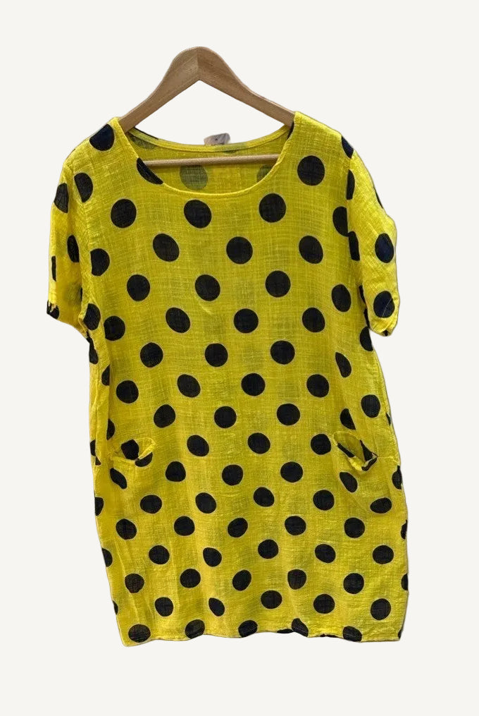 Yellow t-shirt with black polka dots on a hanger against a white background