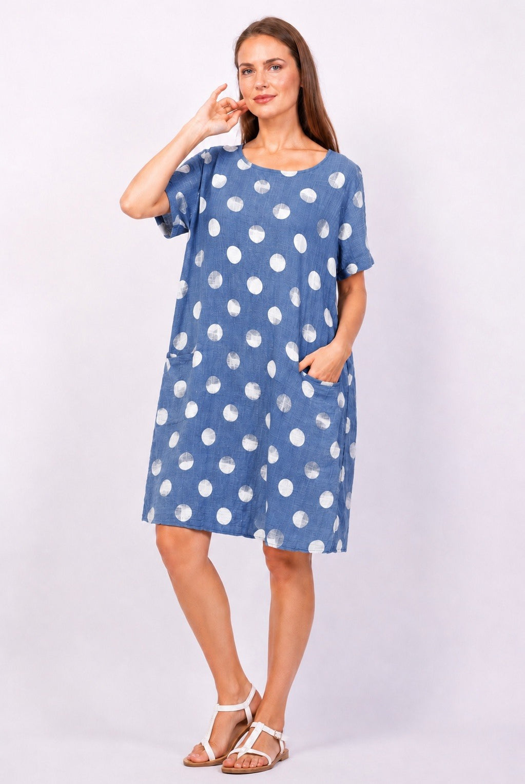 Woman wearing a blue dress with white polka dots on a white background