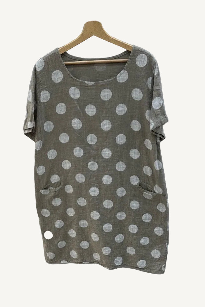 Taupe dress with polka dots on a hanger against a gray background
