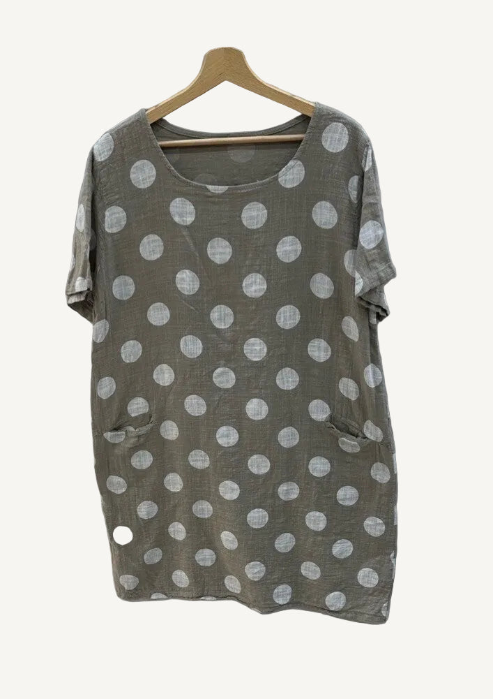 Taupe dress with polka dots on a hanger against a gray background