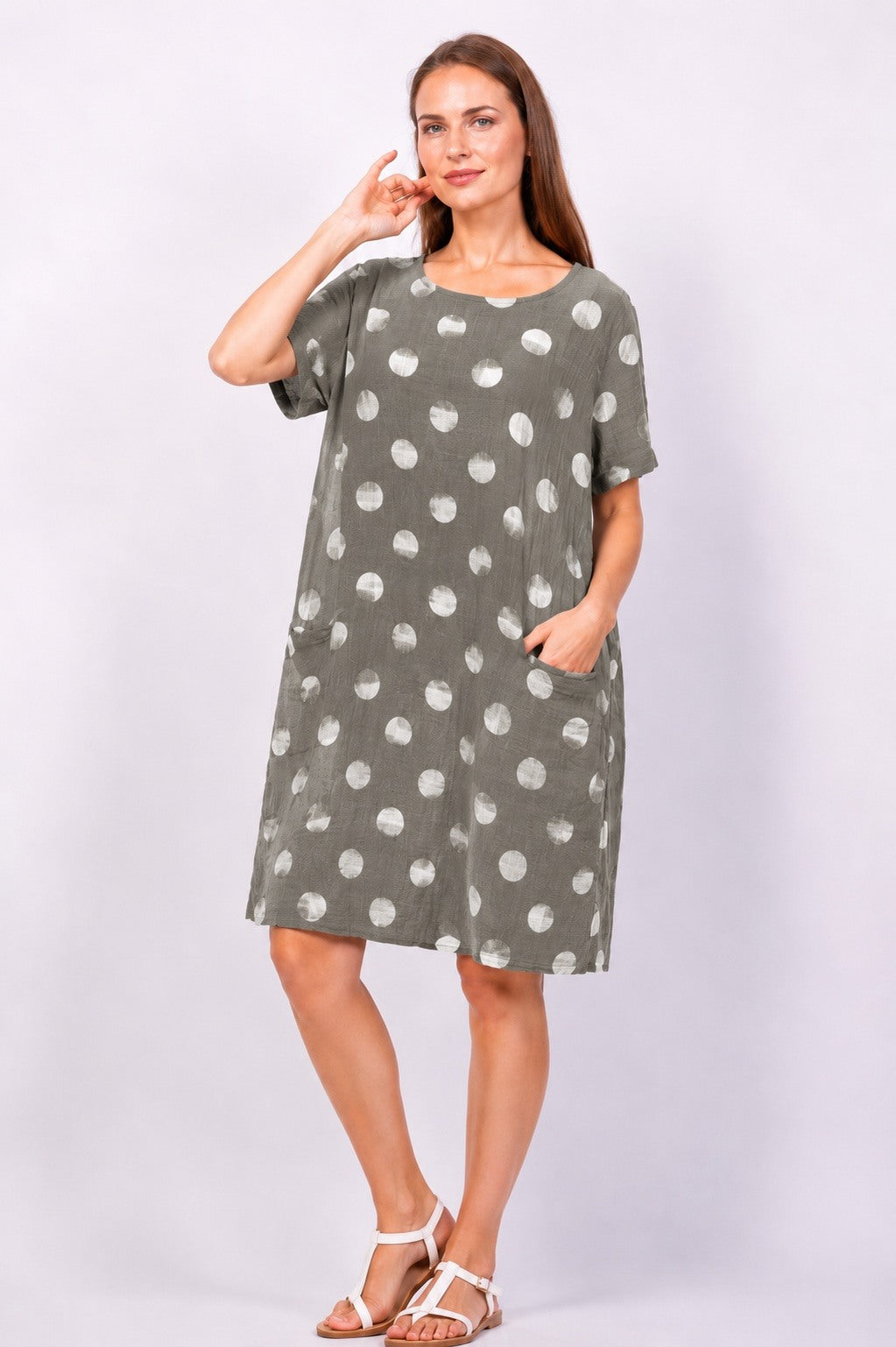 Woman wearing a green dress with white polka dots on a plain background