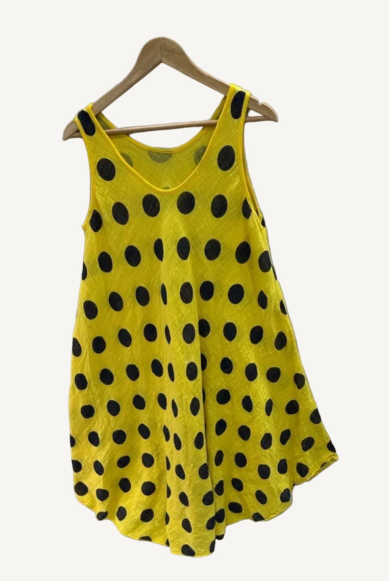 Yellow sleeveless dress with black polka dots on a hanger against a white background